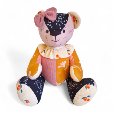 Kleurige stoffen teddybeer met een strik en bloempatronen op de kleding.