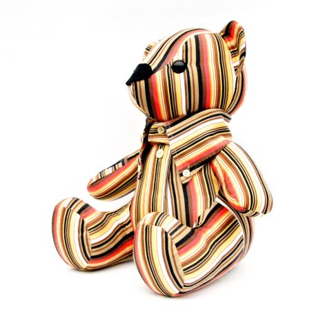 Gestreepte pluche teddybeer met zwarte neus en oogjes.